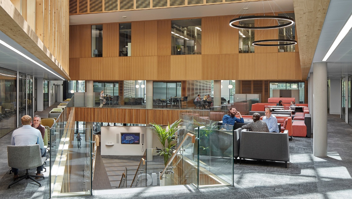 Nexus atrium showing 3 people having a meeting on the sofas and looking down into the events space
