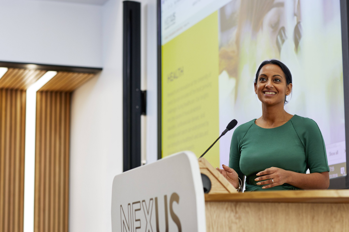 Woman presenting at a lectern in the Nexus lecture theatre