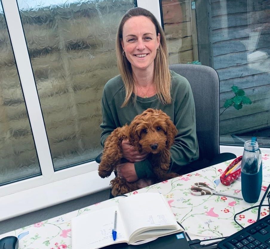 Yvonne McBrearty, Head of Marketing B2B sitting at her remote working desk holding her Cockapoo puppy Rosie