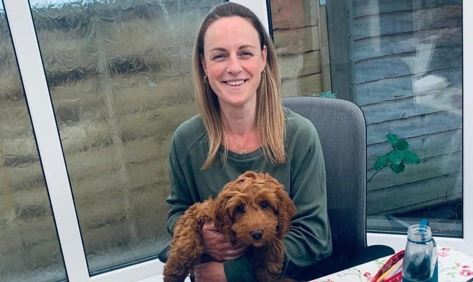 Close up of Yvonne McBrearty, Head of Marketing B2B sitting at her remote working desk holding her Cockapoo puppy Rosie