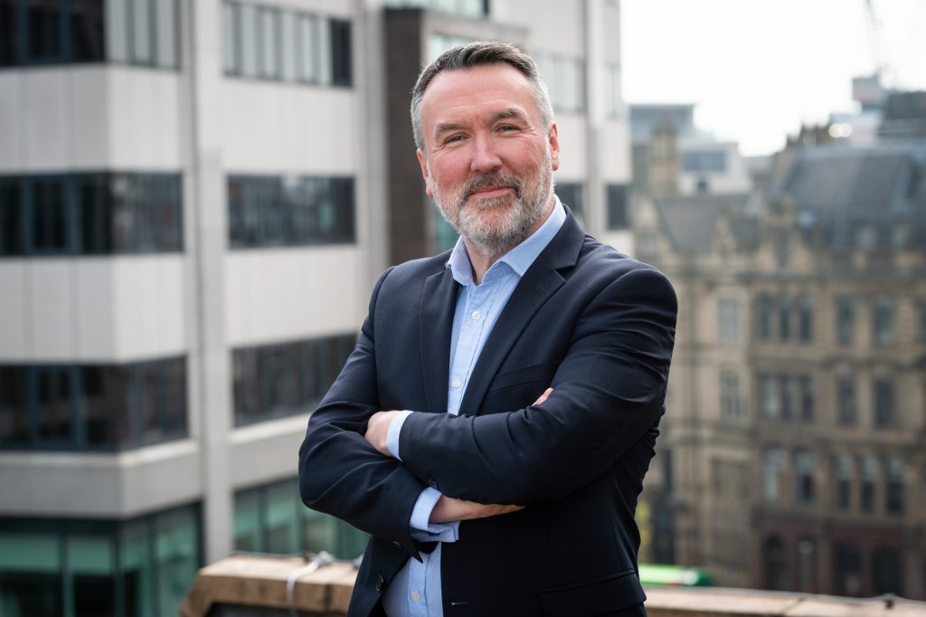 Image of Stuart Clarke, Director of the Leeds Digital Festival stood on a Leeds rooftop balcony with arms folded and smiling to camera