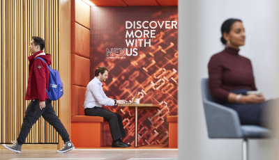 A man working on his laptop in a booth in the Nexus atrium