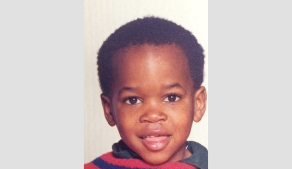 Head and shoulders shot of Delroy Beverley smiling to camera, aged 5