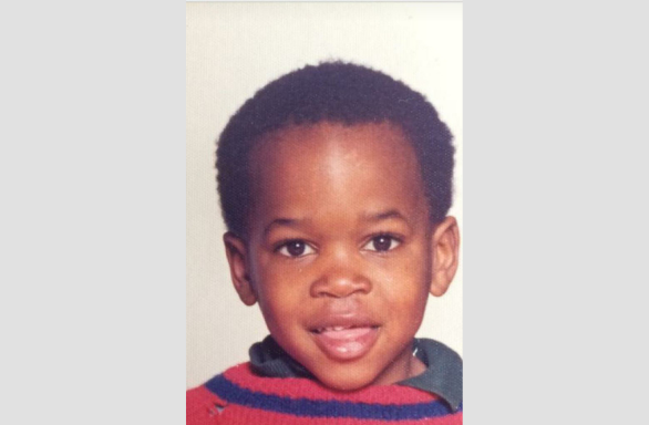 Head and shoulders shot of Delroy Beverley smiling to camera, aged 5