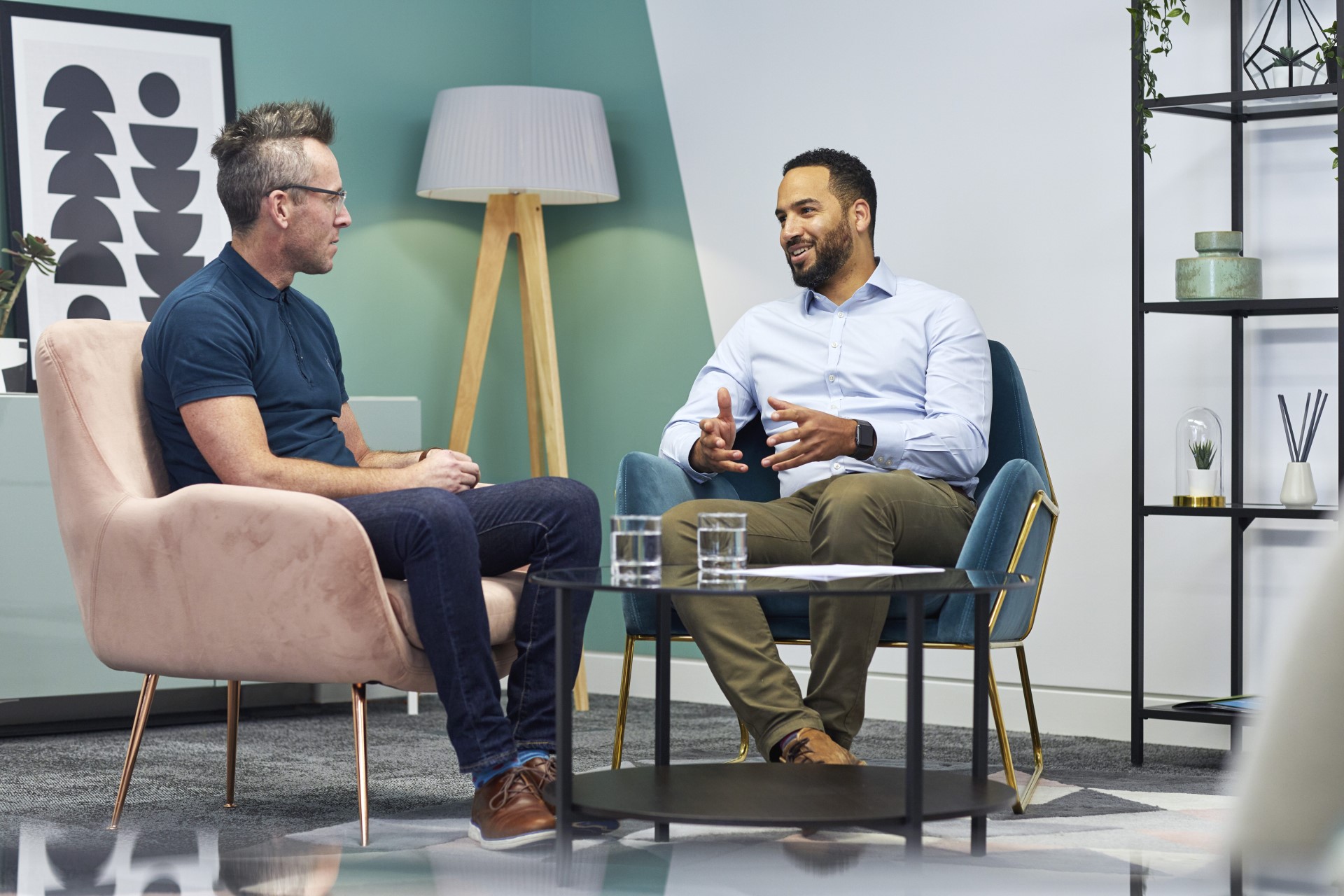 Two male colleagues sat in a casual lounge environment chatting