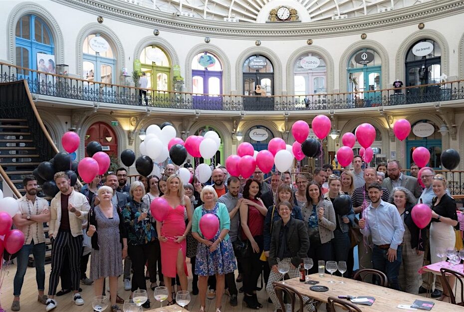 A group of people inside the Corn Exchange holding pink balloons.