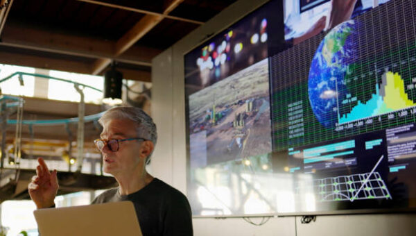 A man talking in front of a powerpoint on the climate.