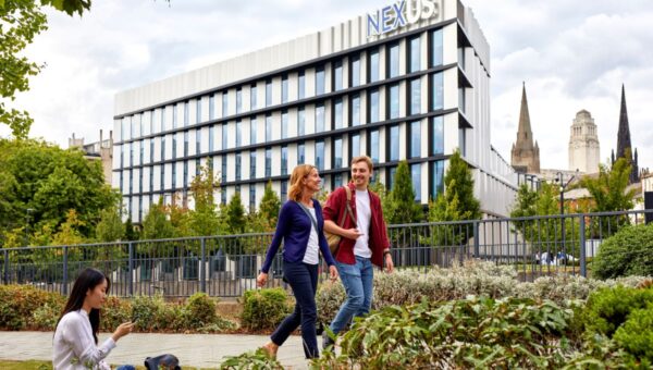 Two people walking in conversation outside of the Nexus building.