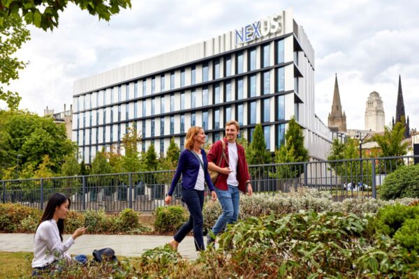 Two people walking in conversation outside of the Nexus building.