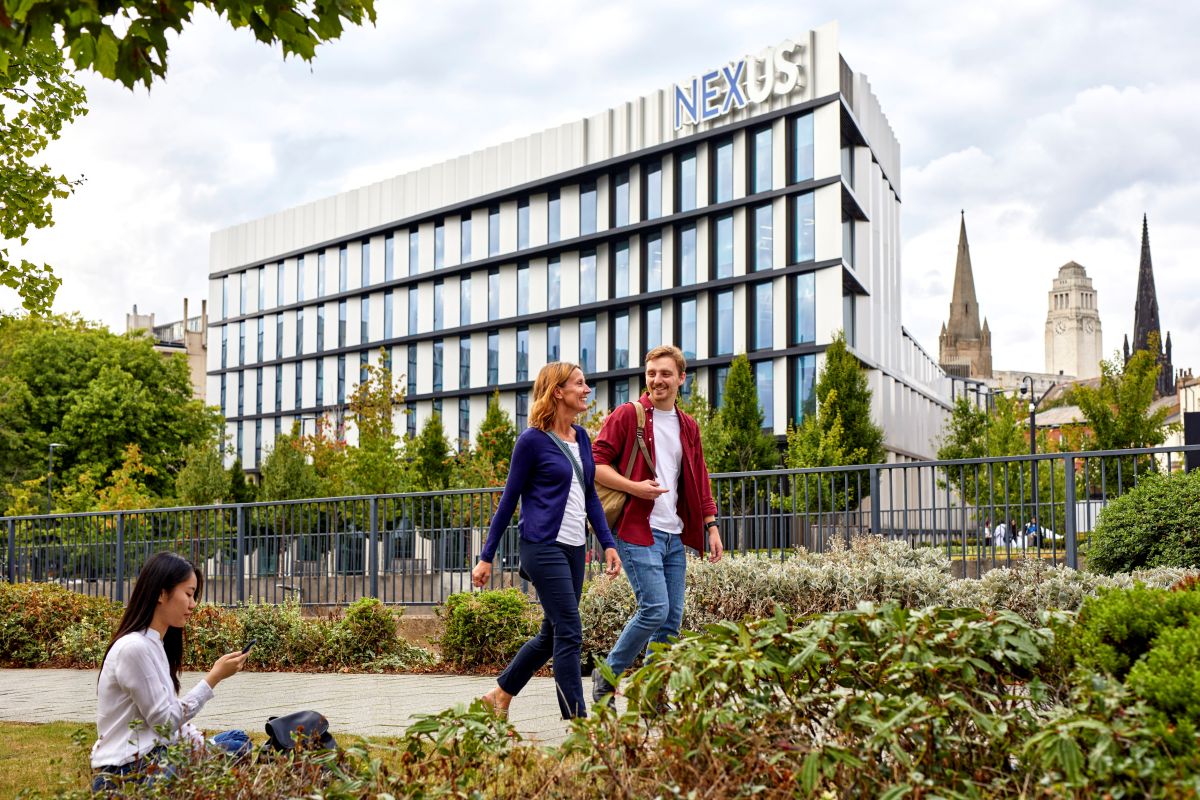 Two people walking in conversation outside of the Nexus building.