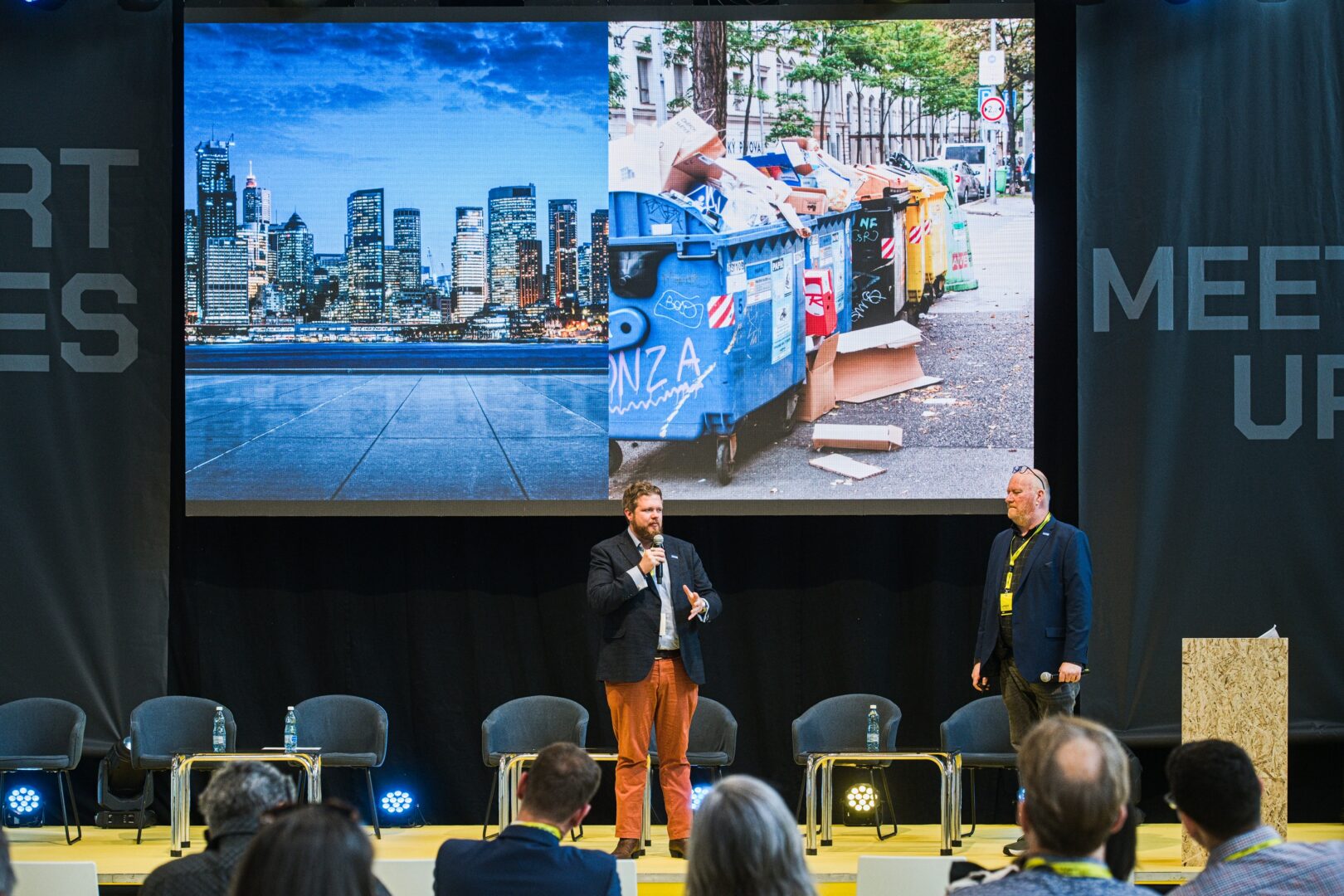 Barry Singleton and Dennis Dokter stand on stage with a presentation behind them