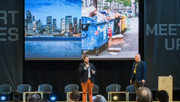 Barry Singleton and Dennis Dokter stand on stage with a presentation behind them