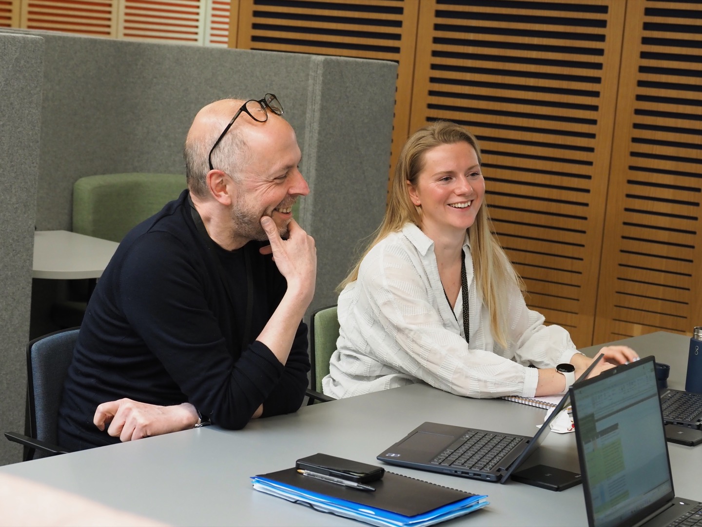 A man and woman sat side by side with a laptop in front of them.